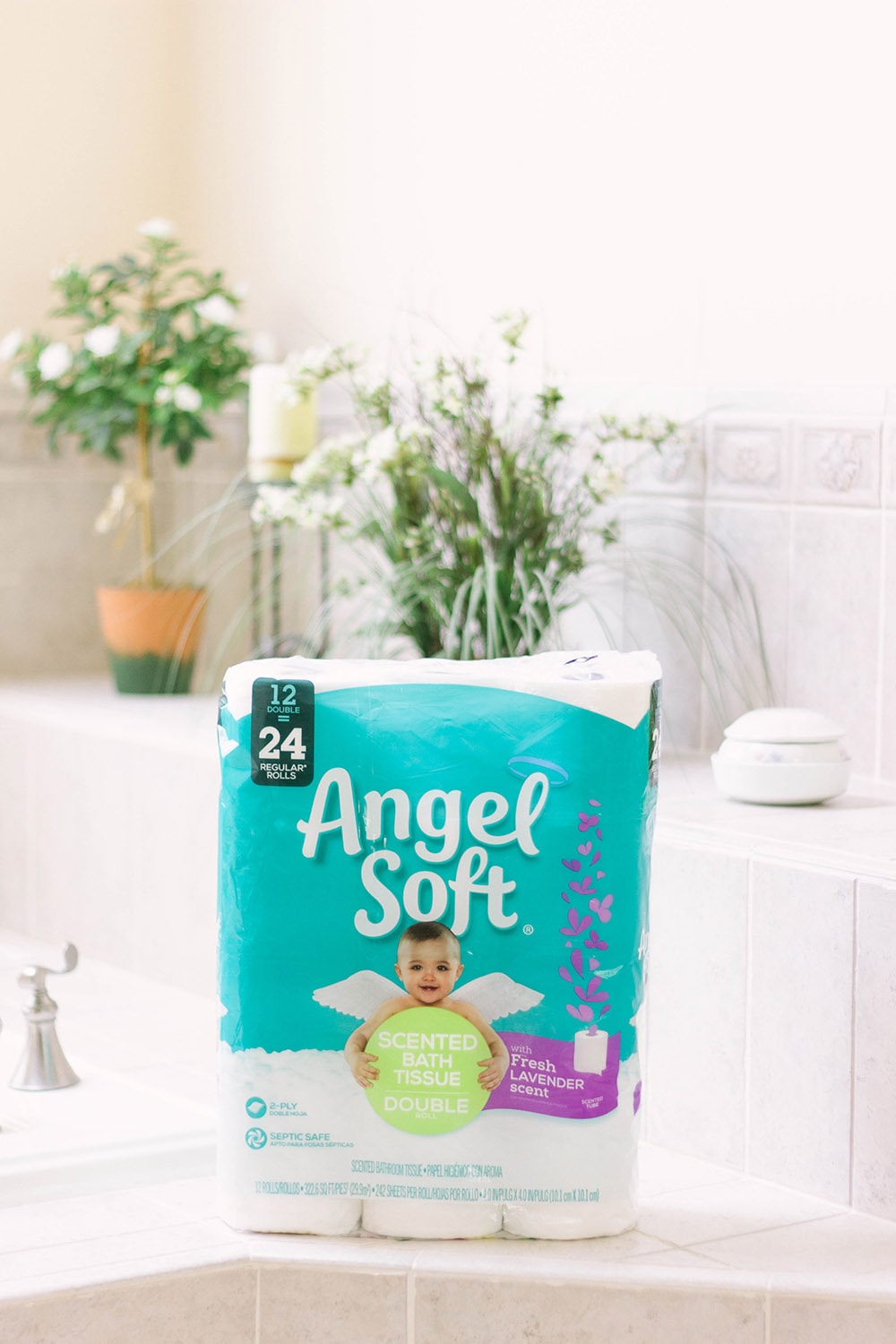 Angel Soft toilet paper sitting on a bathtub ledge. 