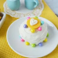 White mini cake on a plate with blue tea set.