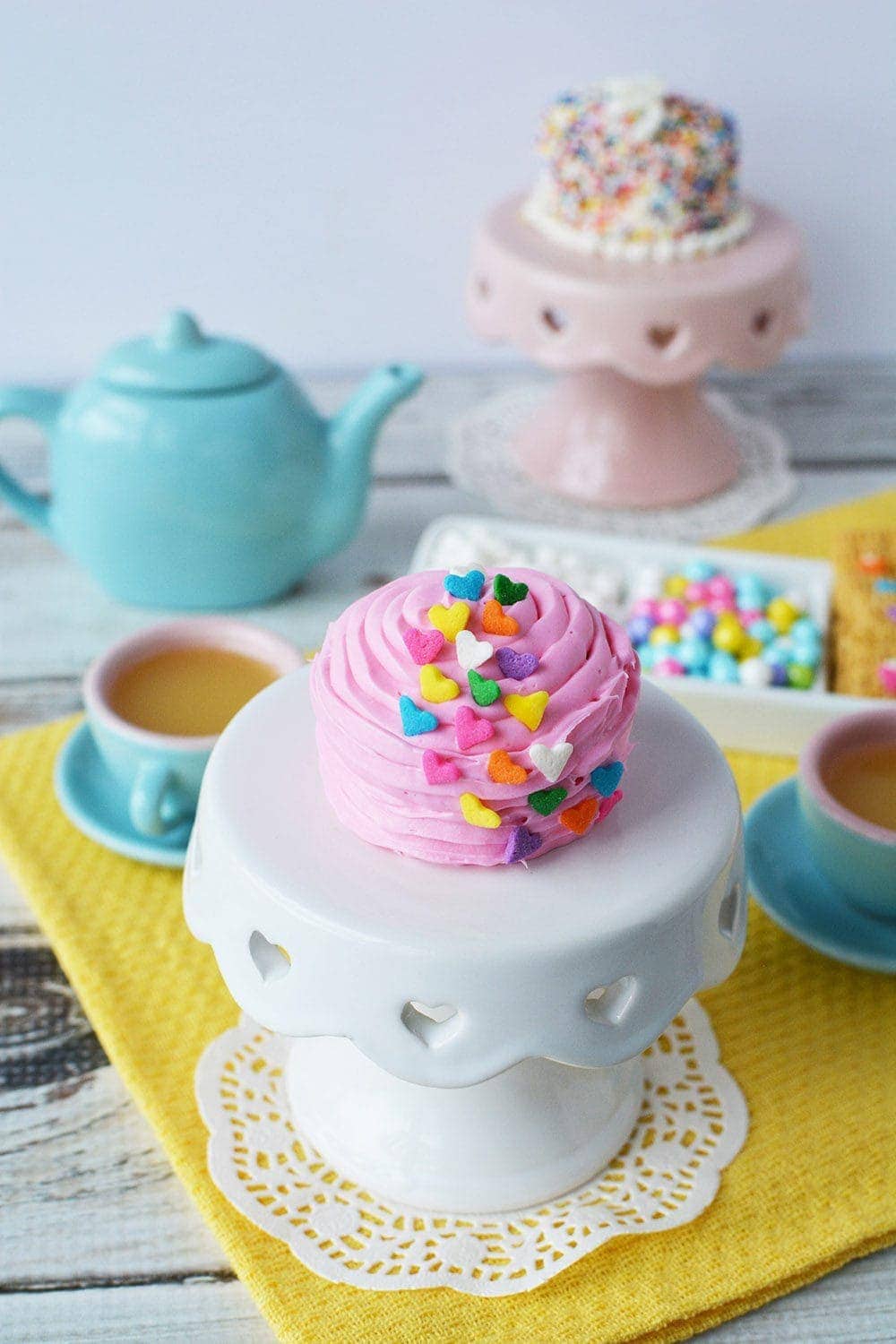 Pink fairy cake on a mini cake stand during a tea party.