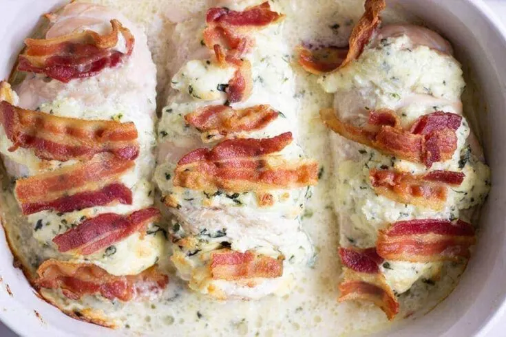 Bacon and spinach Hasselback chicken in a casserole dish.