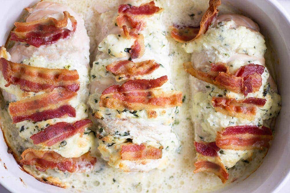 Bacon and spinach Hasselback chicken in a casserole dish. 