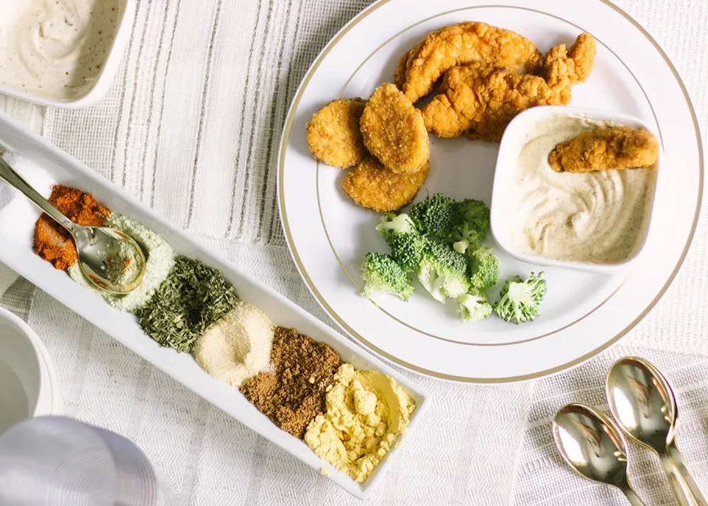 Chicken dipped in dip and overhead shot of seasonings. 