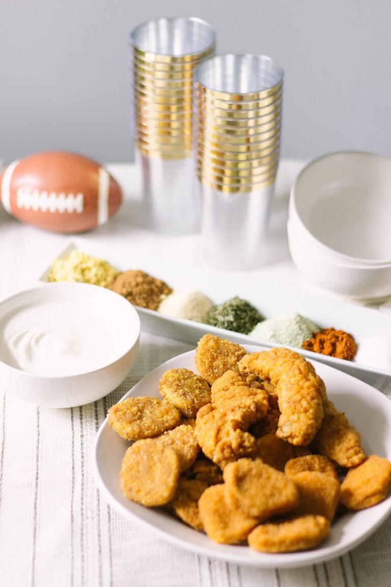 Nuggets and strips in a bowl on a plate with gold settings.
