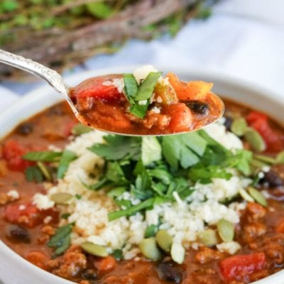 Spoonful of chili over a bowl.