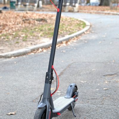 Scooter in the street with leaves in the background.