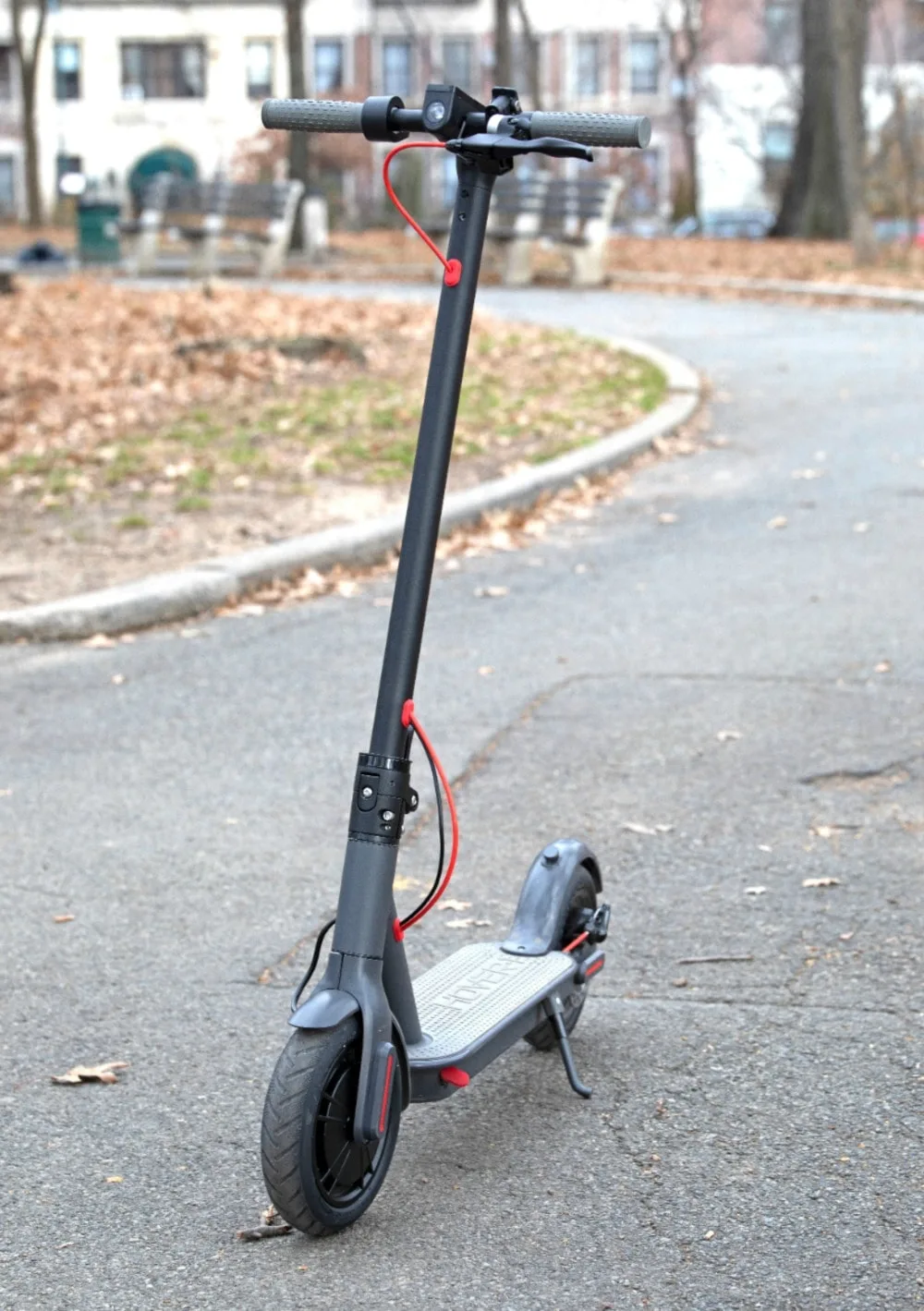 Scooter in the street with leaves in the background. 