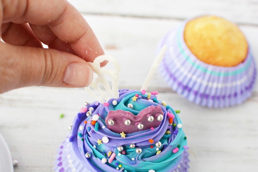 Putting candy wings on a cupcake