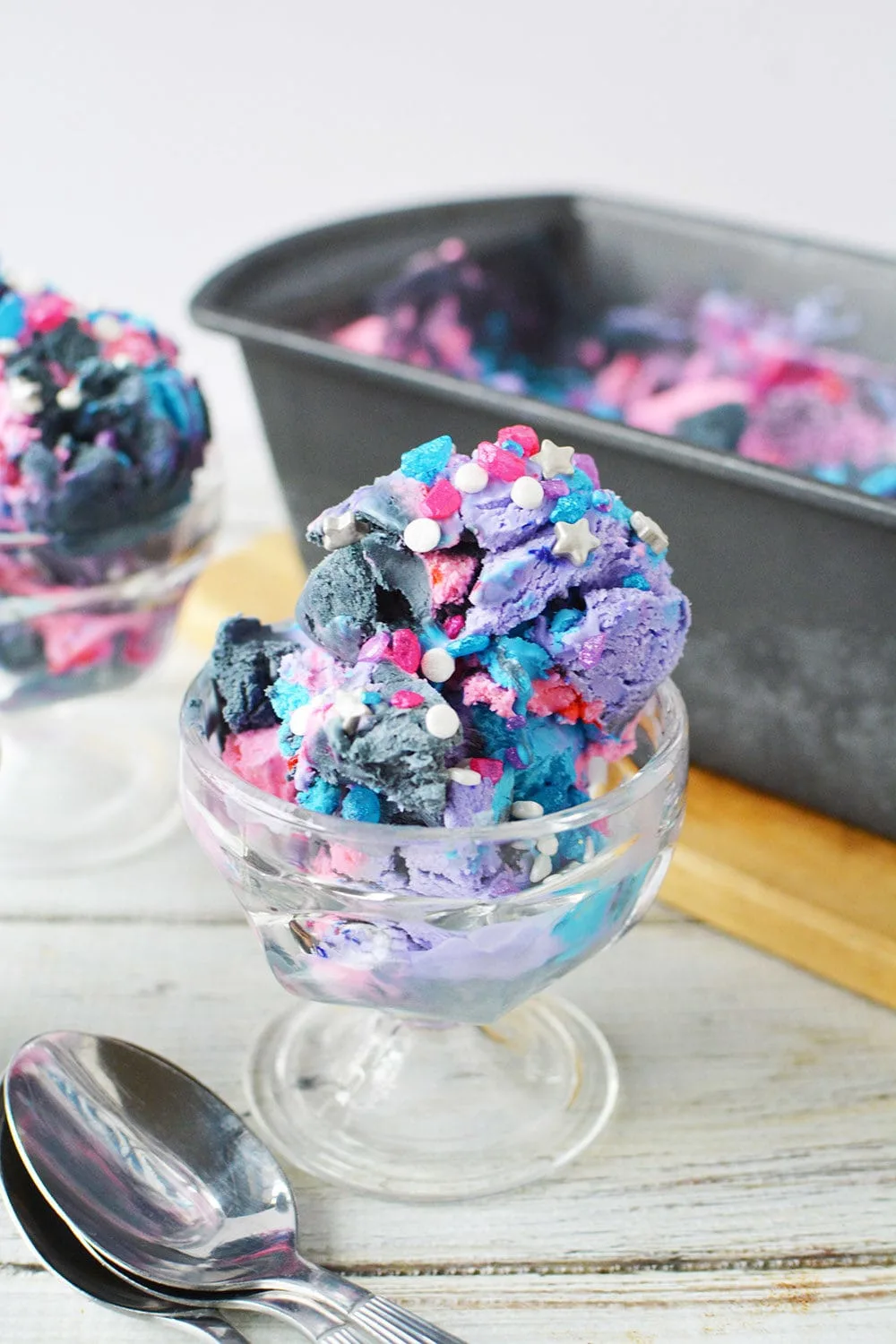 Pink, purple, and gray ice cream topped with sprinkles in a dish. 