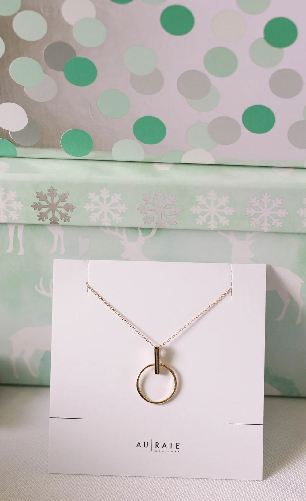 Necklace from Aurate in front of gift boxes.