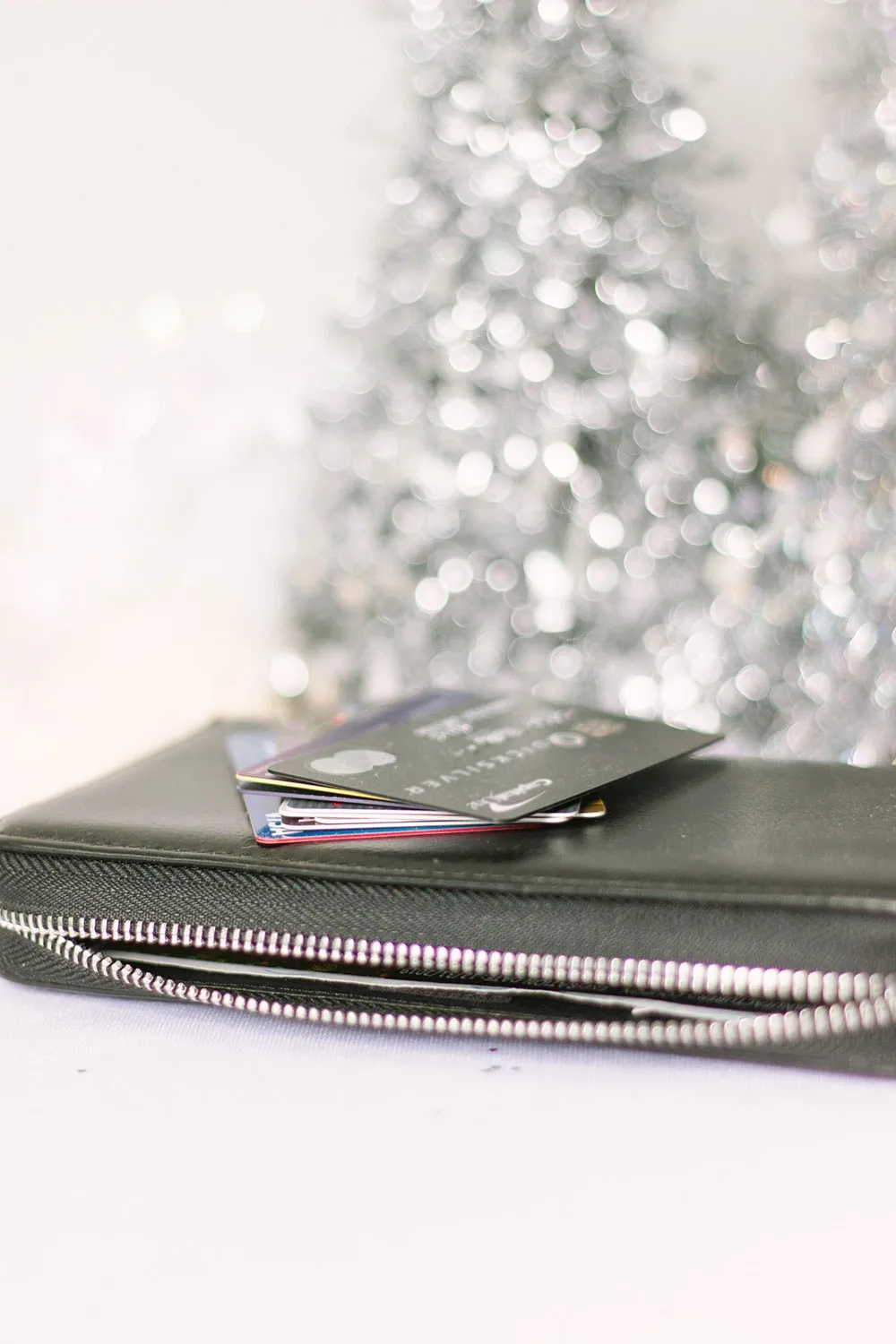 Credit cards on top of wallet in front of a silver tree decoration. 