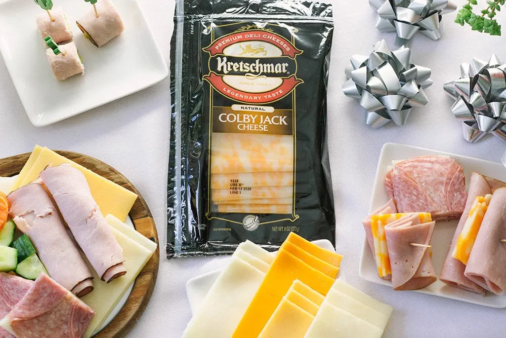 Deli meats and cheeses on plates with bows on the table. 