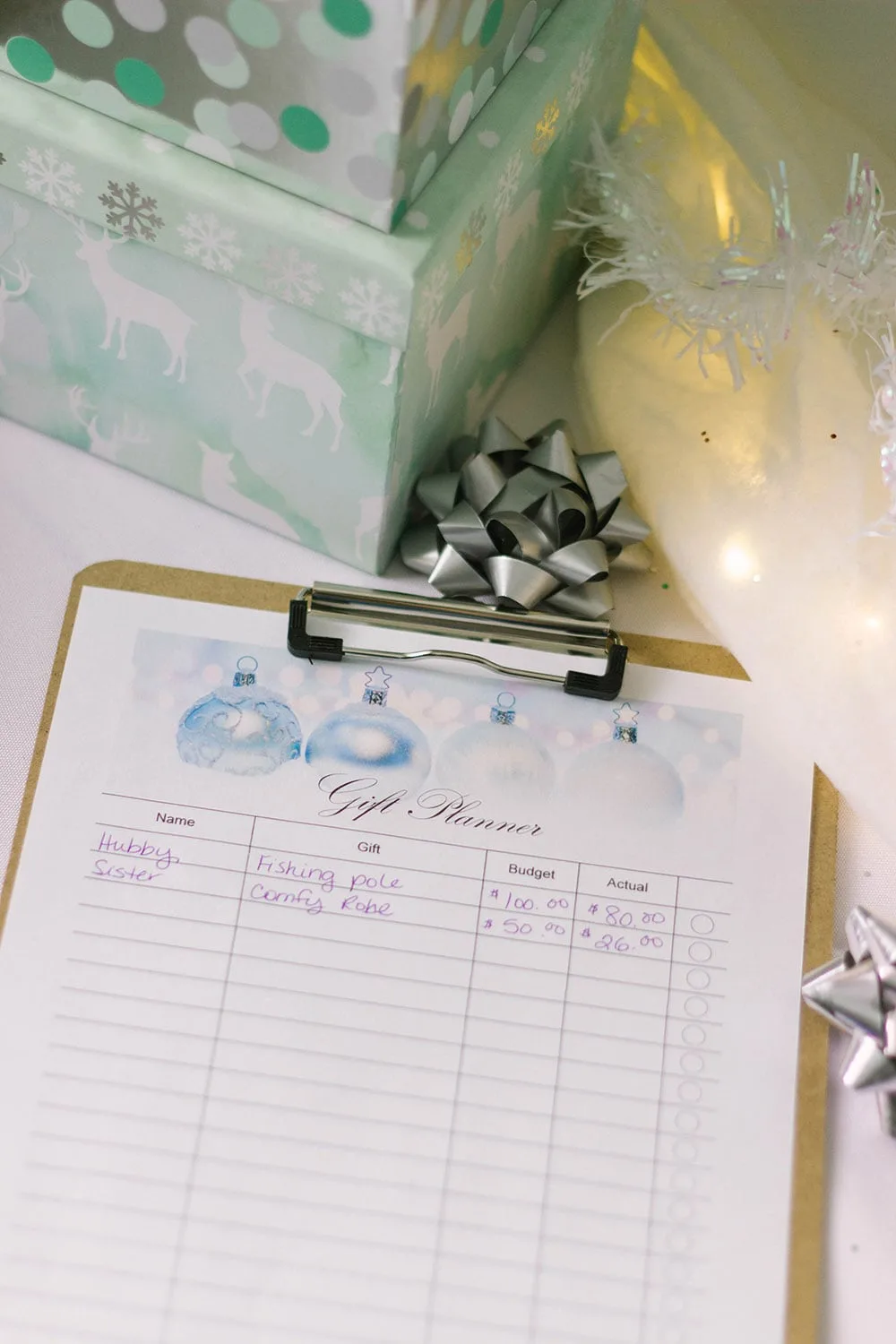 Gift tracker sheet on a clipboard next to a bow and gift box. 