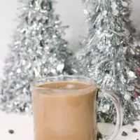 Glass of low car hot chocolate in front of silver Christmas trees
