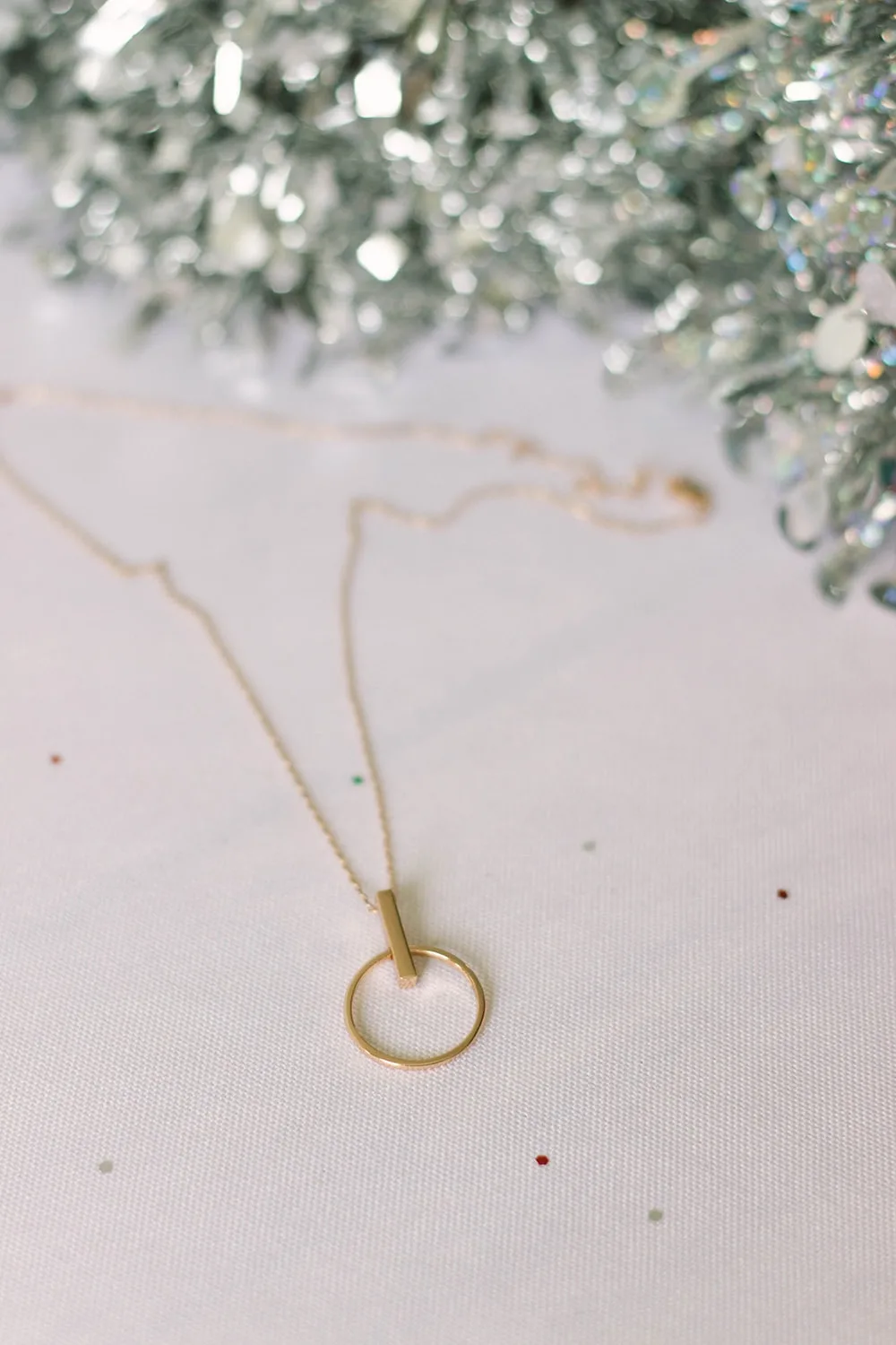Rose gold necklace in front of tree.