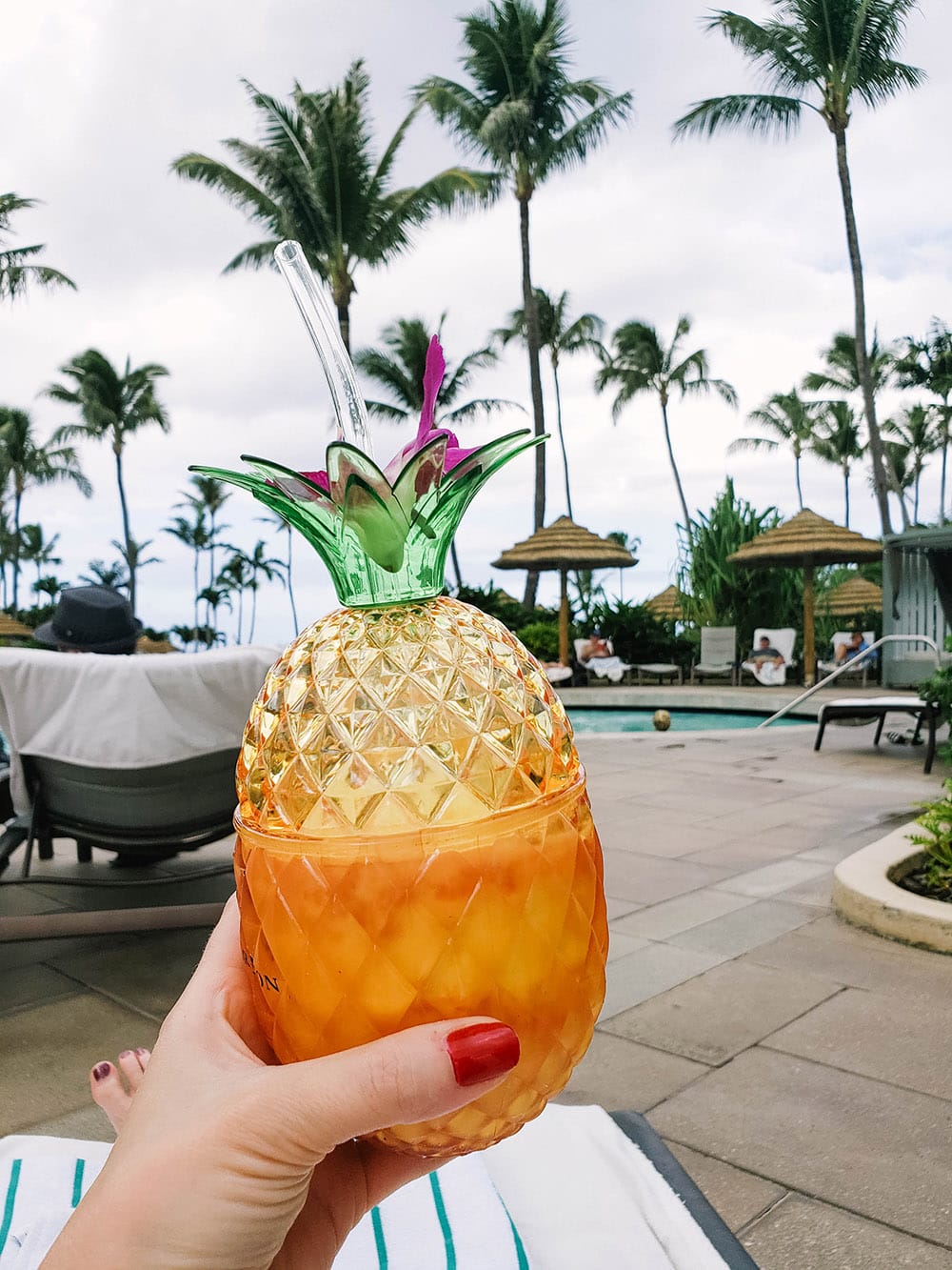 Pineapple drink by a pool and palm trees. 