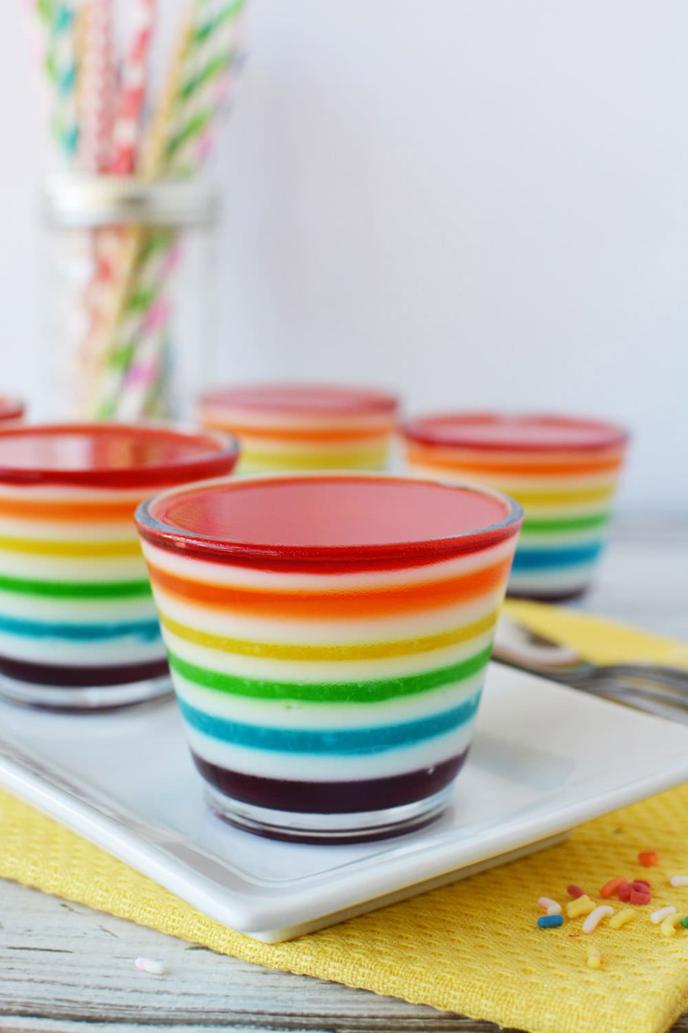 Cups of rainbow Jell-o layers on a table.