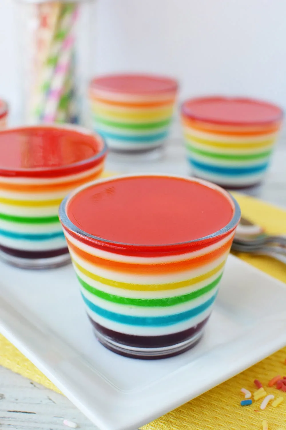 Rainbow Jell-o cups on a table.
