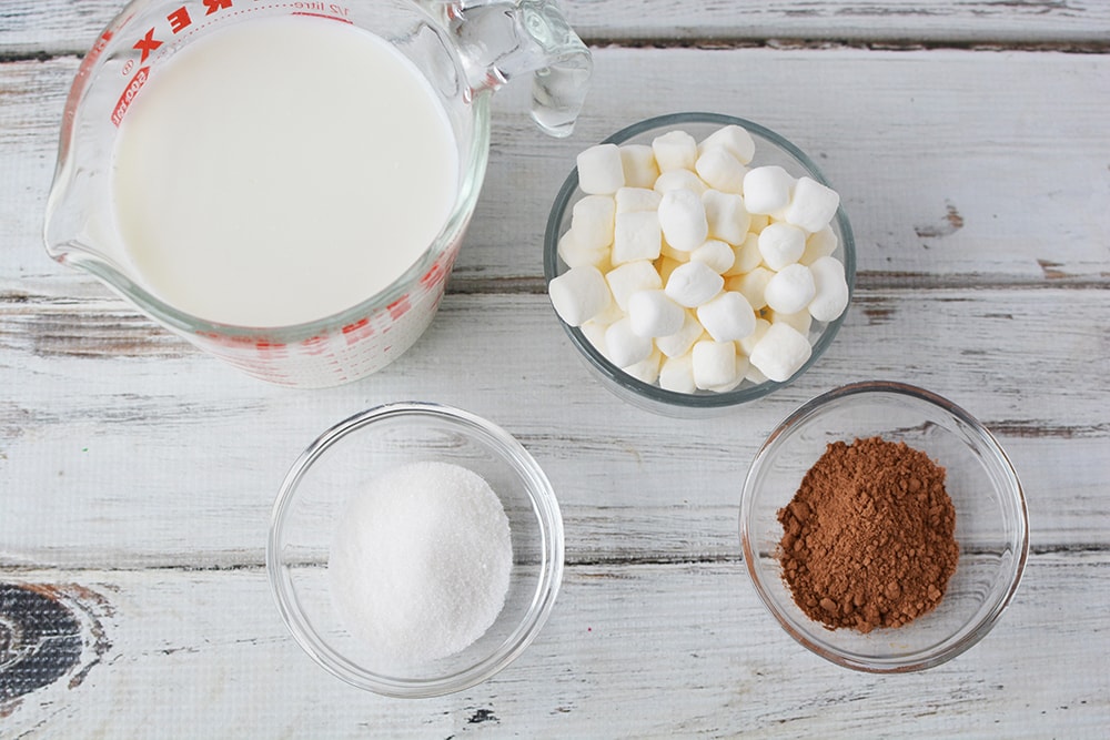 Milk, sugar, marshmallows, and cocoa in bowls. 