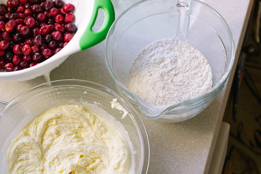 Cranberries, flour, and cake batter in bowls. 