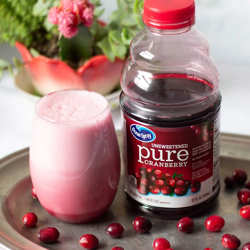 Cranberry juice slushy next to the bottle of juice and cranberries. 