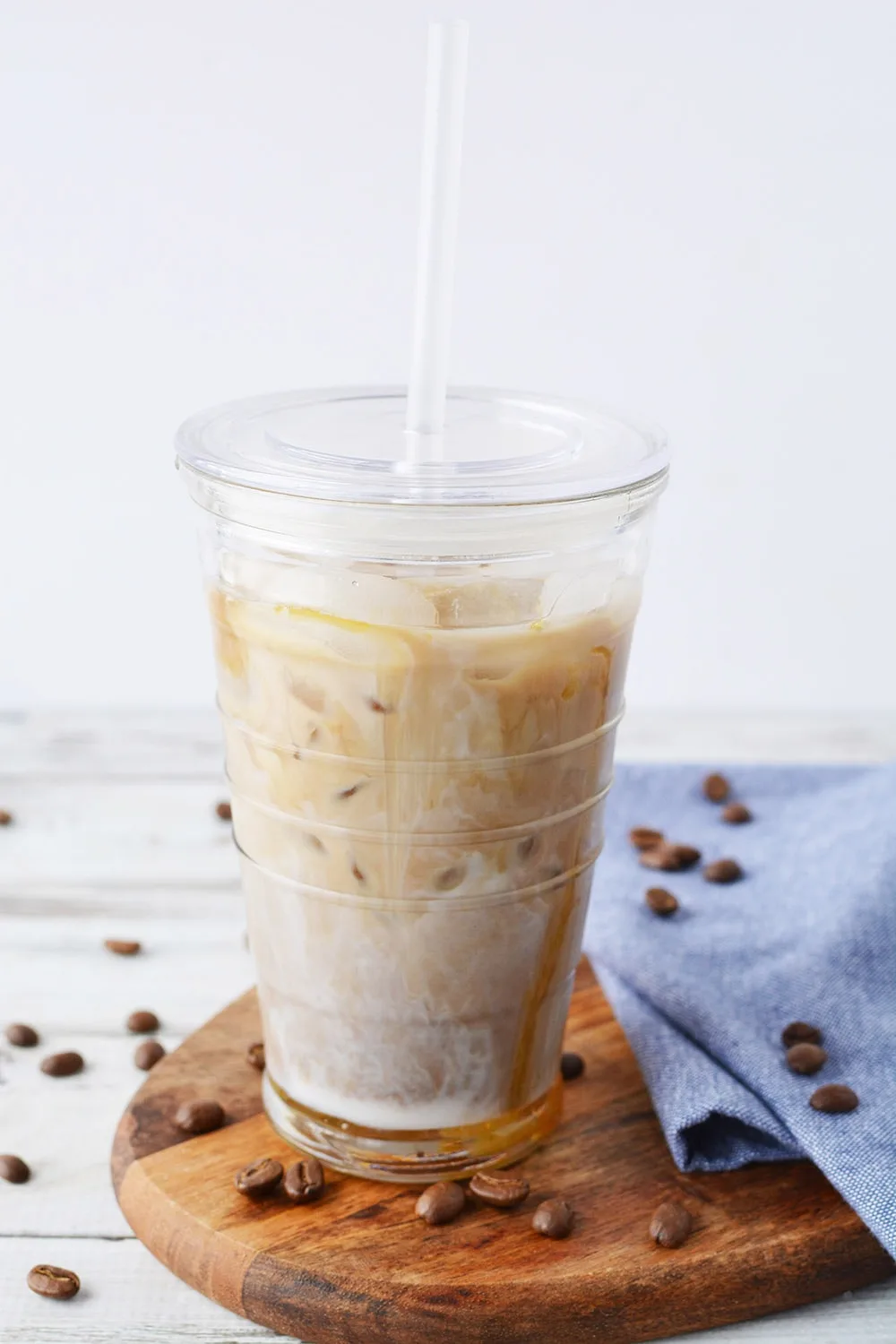 Iced coffee with caramel in a tumbler with straw.