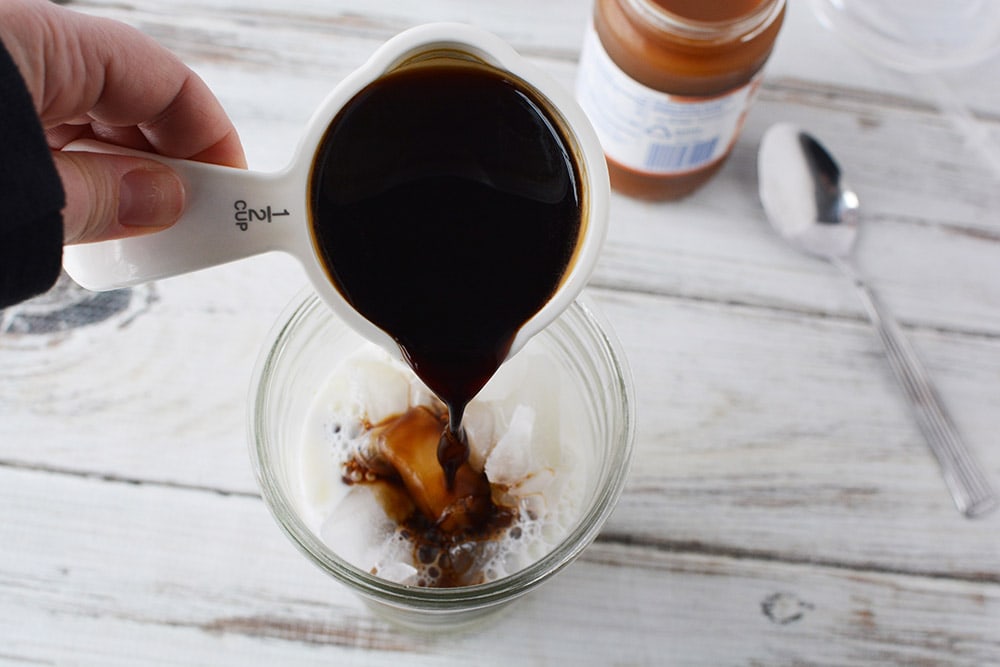 Strong coffee pouring into glass.