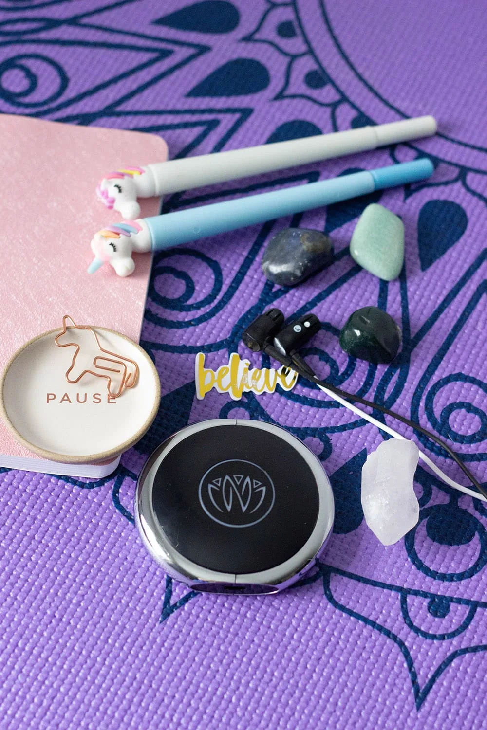 Relaxing items on a purple yoga mat.