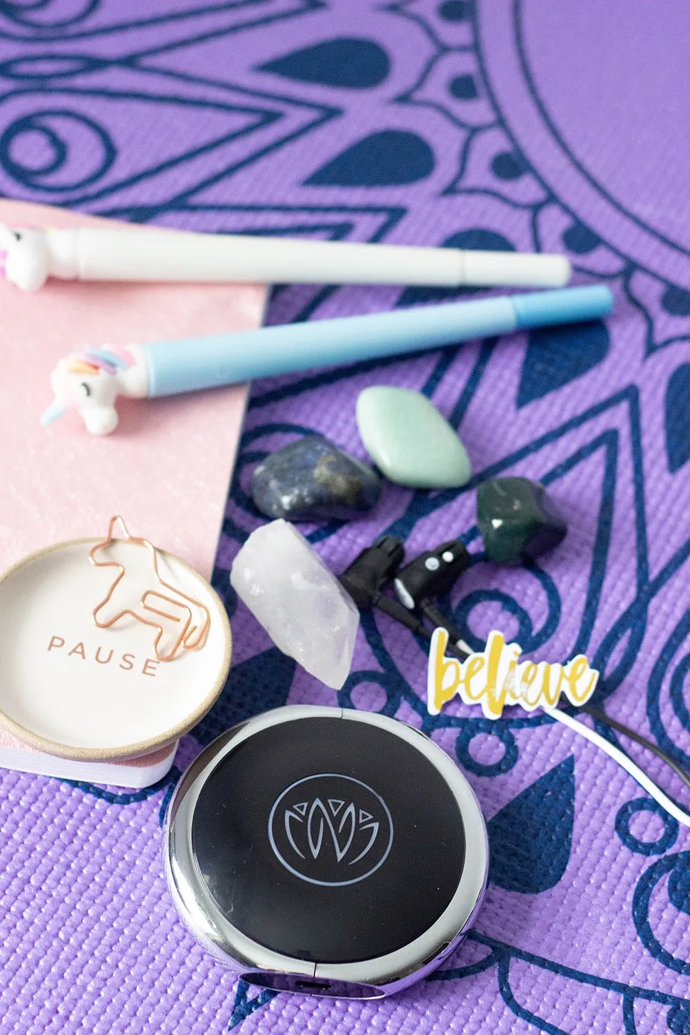 Unicorn pens, stones, and Zen unit on a yoga mat.