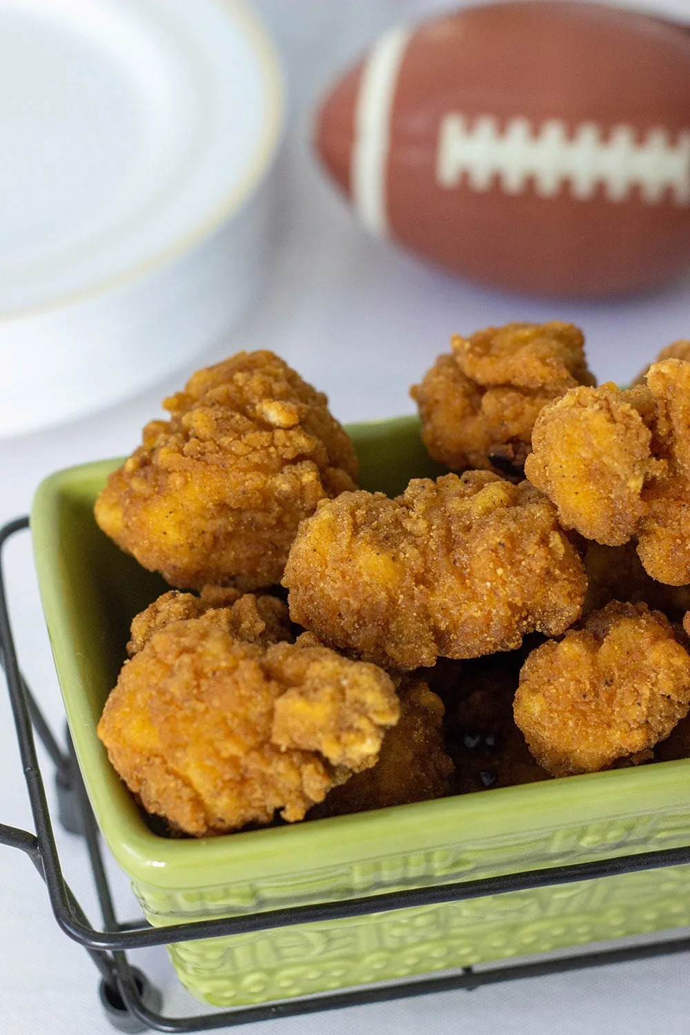 Popcorn chicken next to a football. 