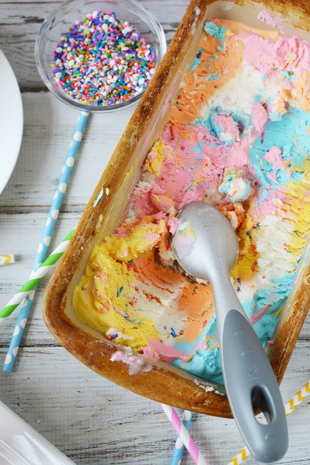 Pan of unicorn ice cream with scoops taken out.