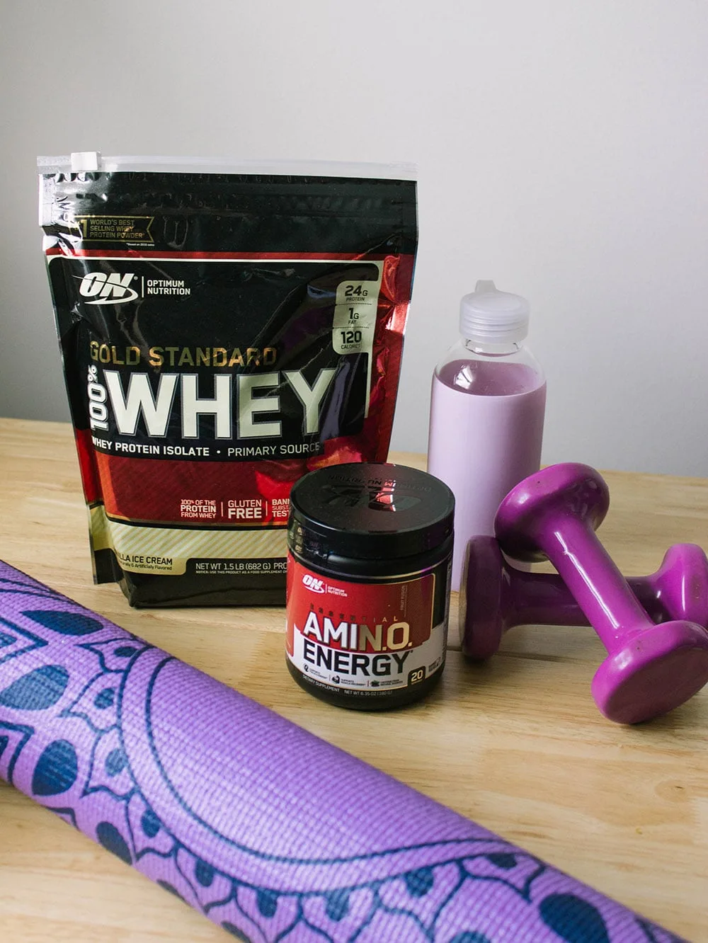 Yoga mat and protein supplements on a table. 