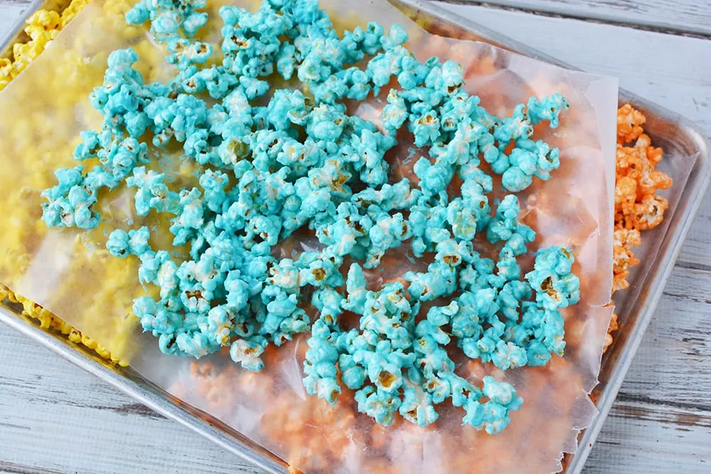 Layers of colored popcorn on a baking sheet.