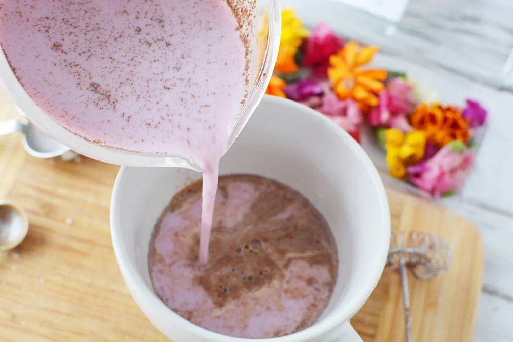 Adding cinnamon milk to a mug.