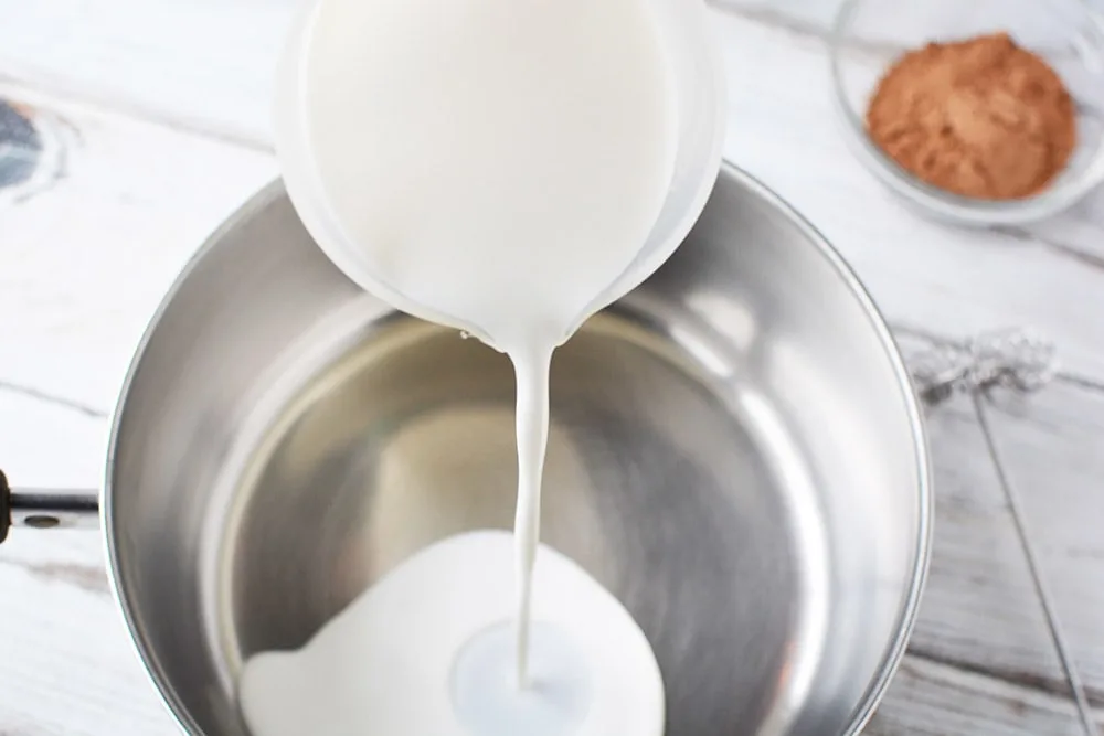 Pouring milk into a saucepan.