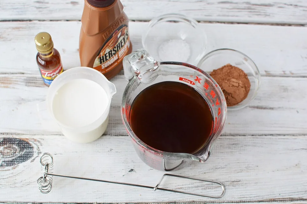 Syrup, milk, coffee, and other ingredients to make a salted caramel drink. 