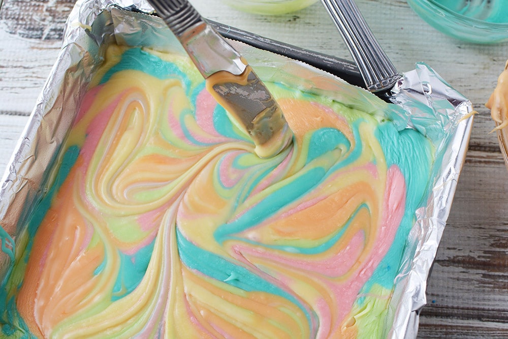 Swirling rainbow colors of fudge in a pan.
