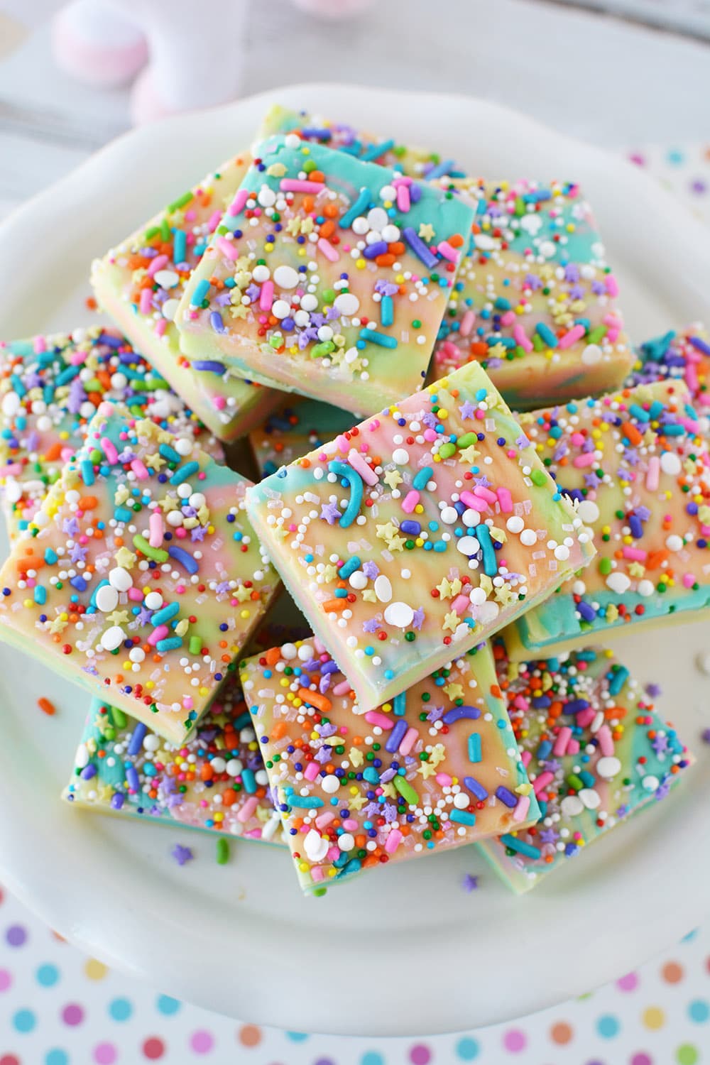 Sliced rainbow fudge with sprinkles on a plate. 