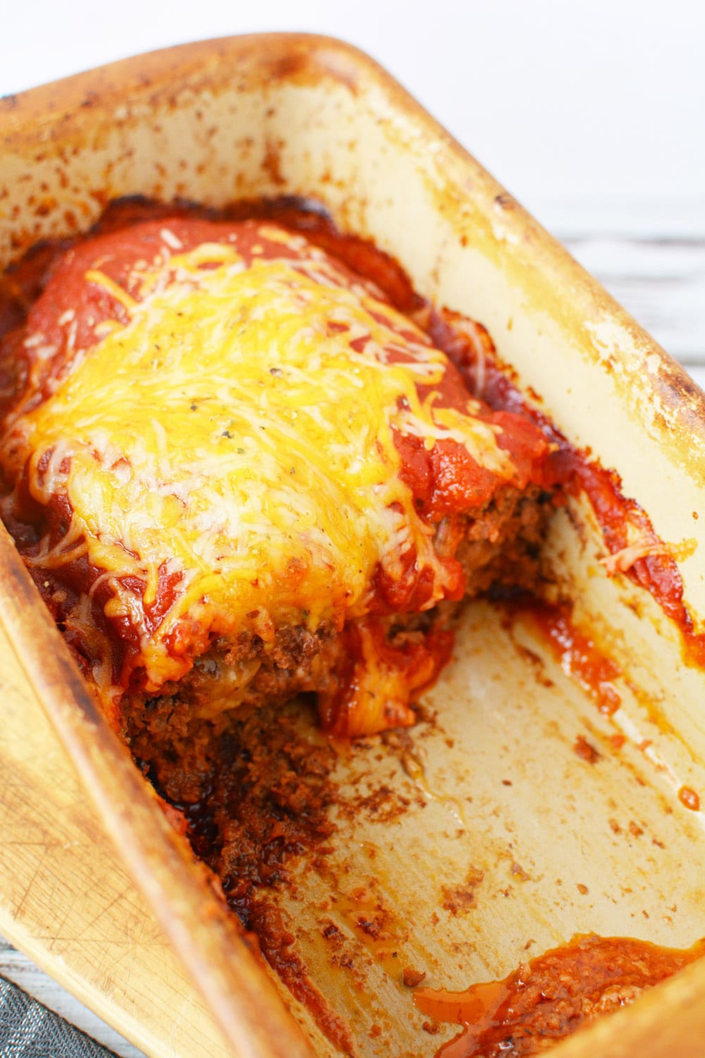 Baked meatloaf with cheese in a loaf pan.