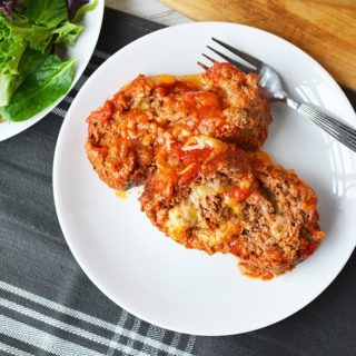 Cheese stuffed meatloaf on a plate next to a salad