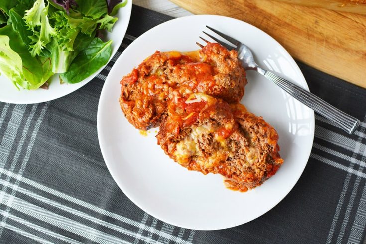 Cheese stuffed meatloaf on a plate next to a salad