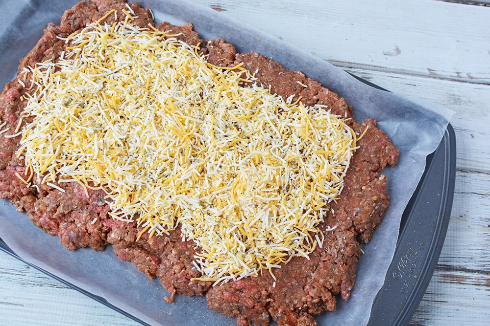 Meatloaf on sheet pan topped with cheese.