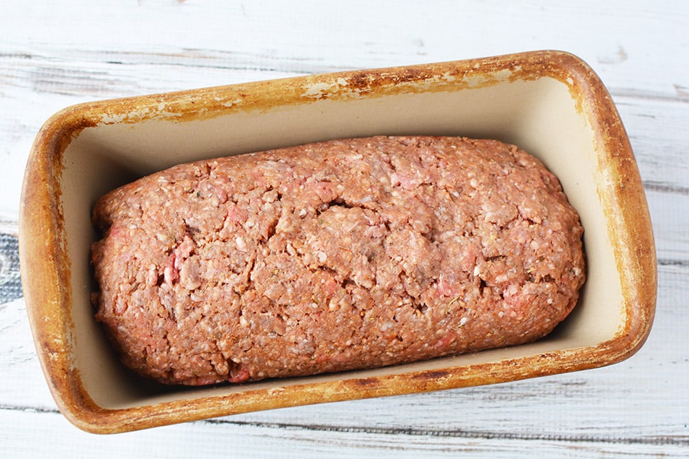 cheese stuffed meatloaf in a loaf pan ready for oven