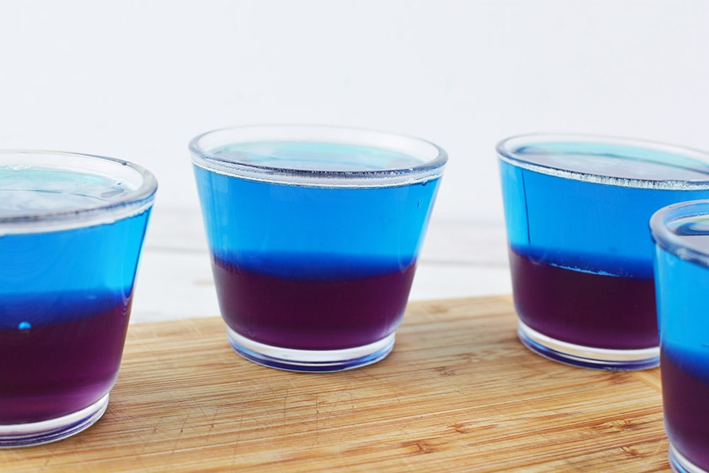 Purple and blue layered jello in small cups. 