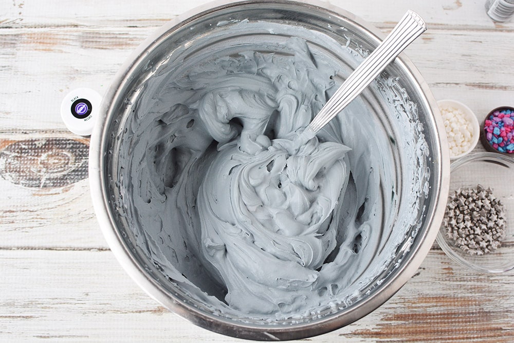 Mixing black food coloring into whipped cream to make it gray. 