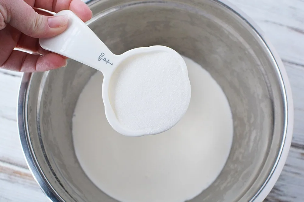 Adding 1/4 cup of sugar into a mixing bowl. 