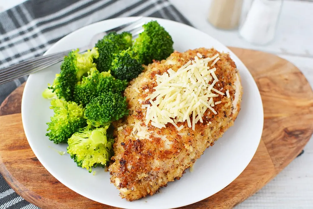 Parmesan crusted chicken on a plate with broccoli.