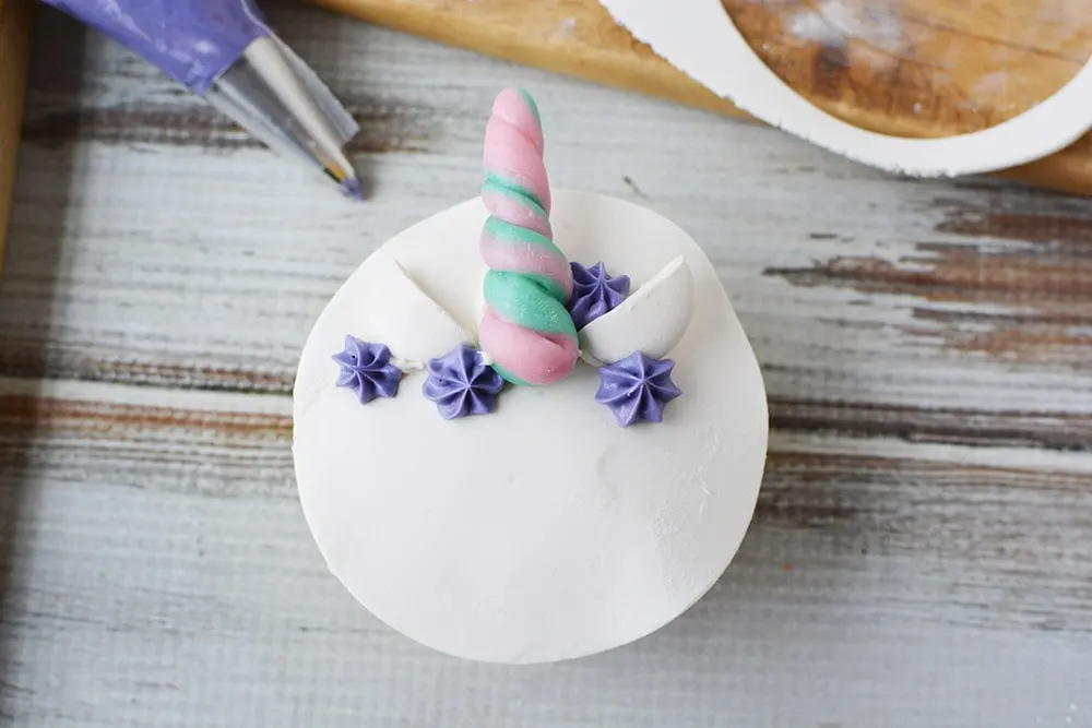 Decorating a unicorn cupcake with purple frosting. 
