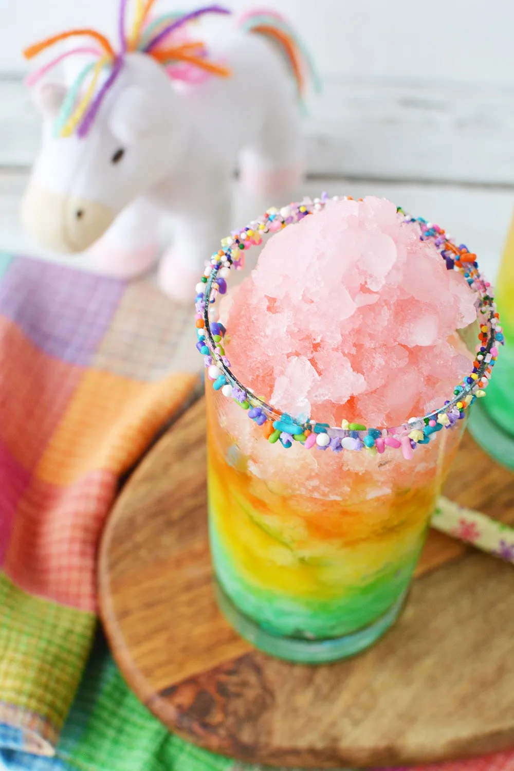 Rainbow lemonade with icy layers in a glass.