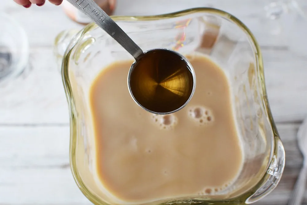 Adding syrup to a blender with coffee mixture. 