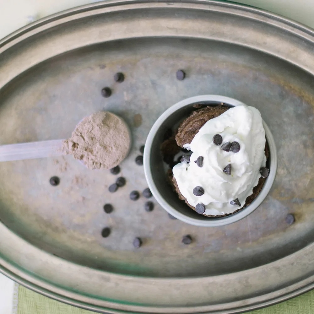 Overhead shot of keto chocolate mug cake with whipped cream and chips.